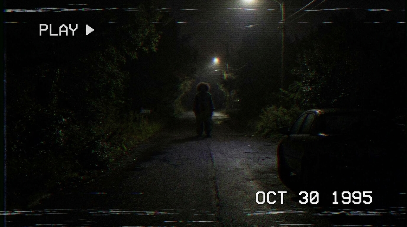 Grainy found-footage-style hotel hallway with a distant clown figure illustrating hidden clues in Hell House LLC.